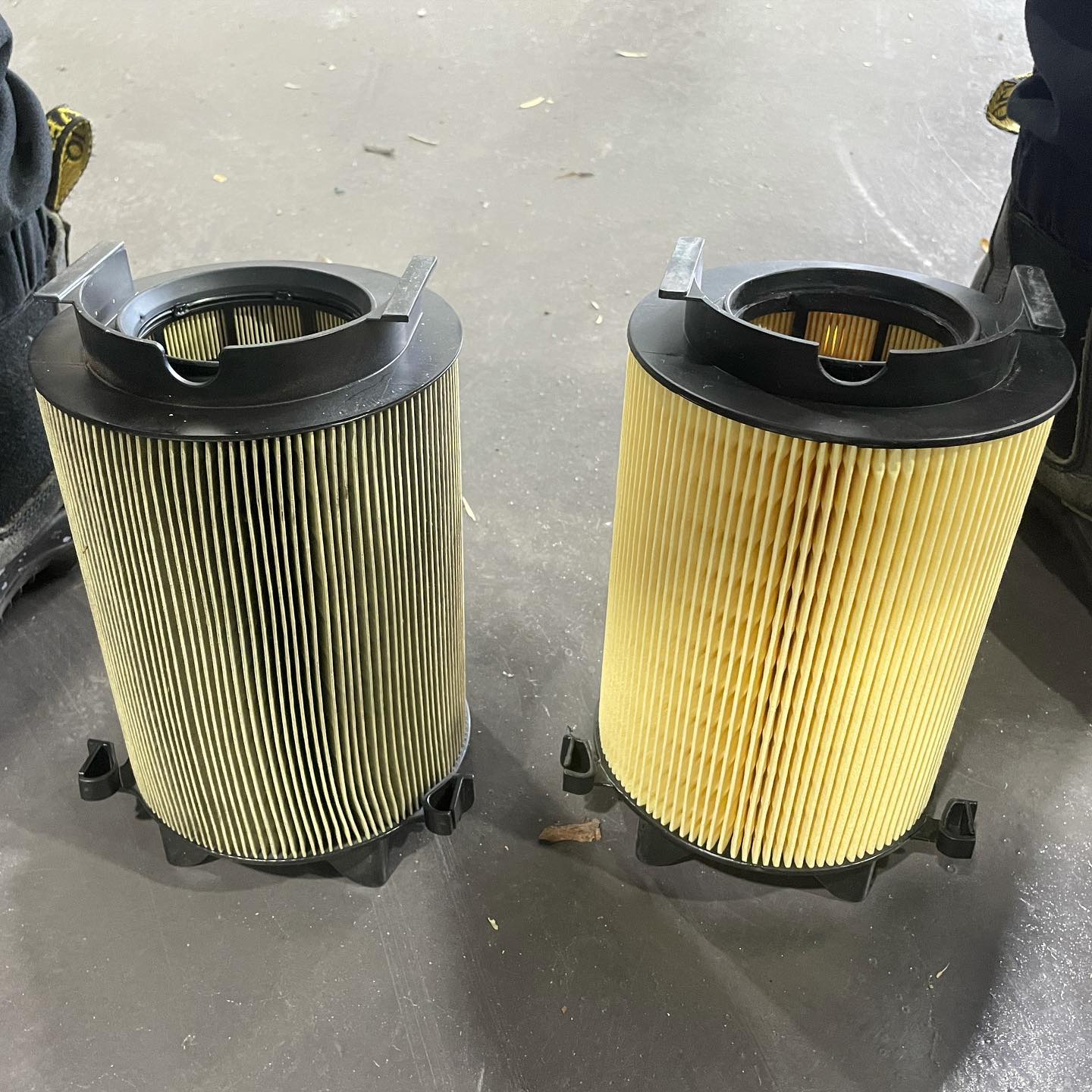 A dirty air filter beside a clean new one on the workshop floor at LP Automotive