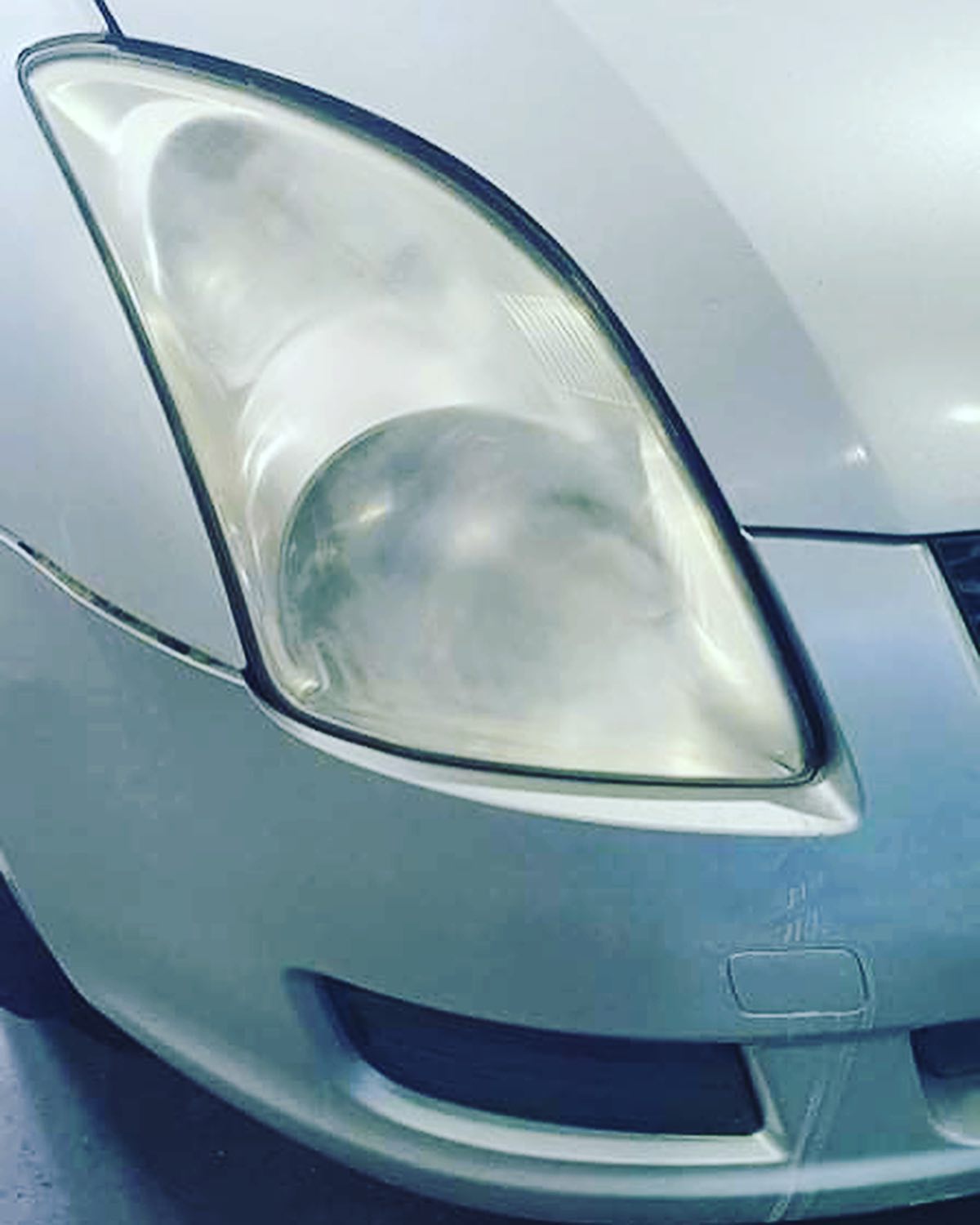 A hazy, yellowed headlight lens before polishing